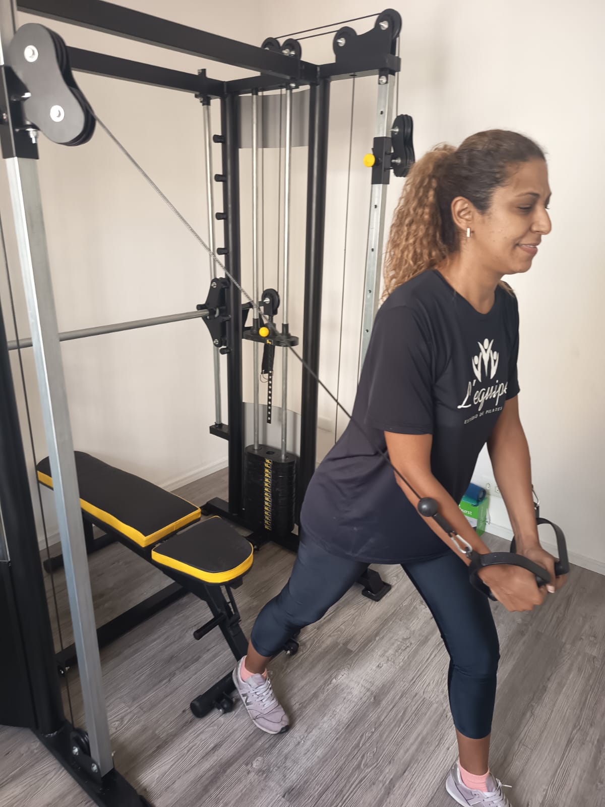 Instrutora da L'équipe demonstrando exercício na estação de cabos do novo espaço de musculação